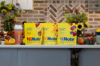Three HiNote Everyday Energy pouches (Strawberry Lemonade, Juicy Peach, Berry Medley) with shaker bottle on a kitchen counter
