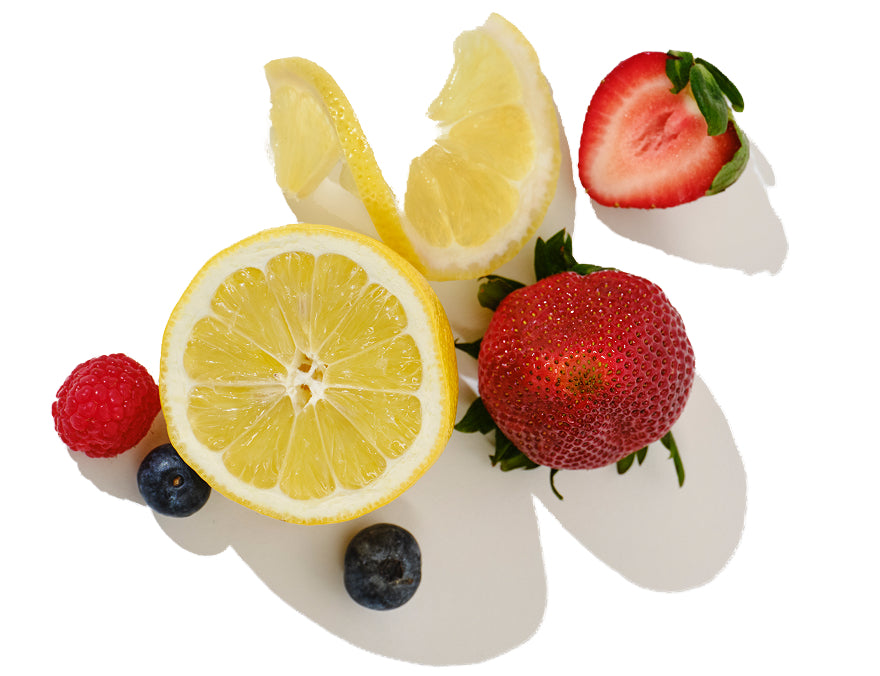 Close-up of lemon halves and mixed berries showcasing a sliced lemon, strawberry, raspberry, and blueberries on a white background