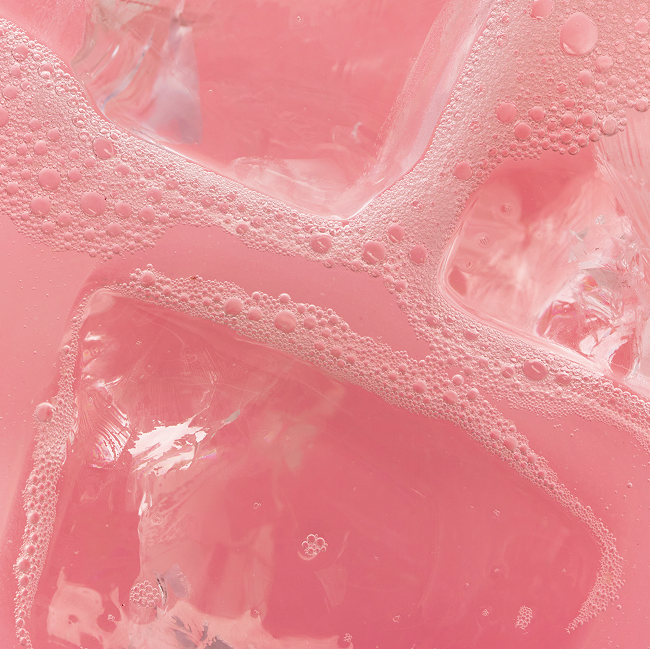 Close-up of HiNote pink beverage showcasing ice cubes and fizzy bubbles on the liquid surface