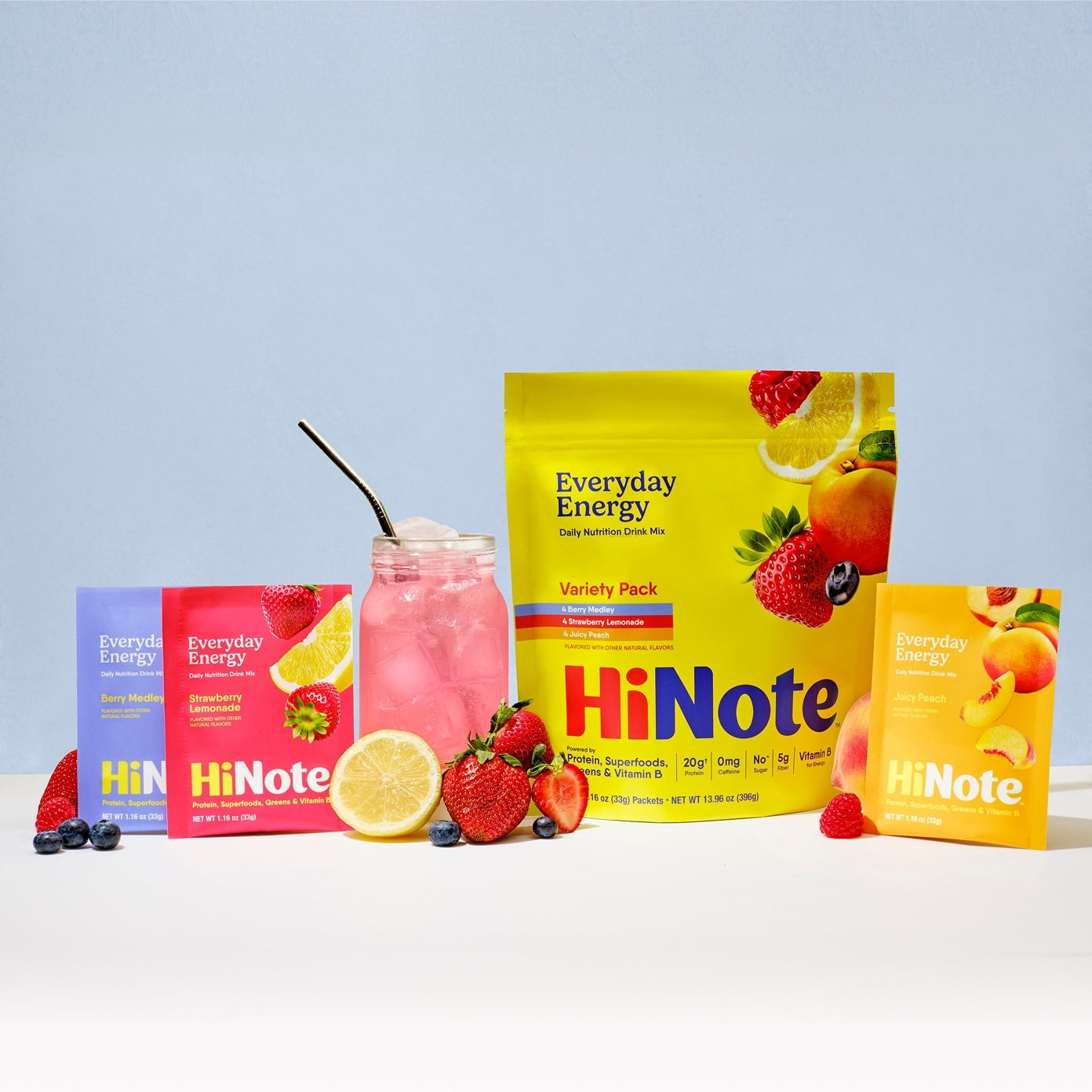 Front view of HiNote Everyday Energy variety pack pouch and sachets with pink drink and fresh berries on pale blue background